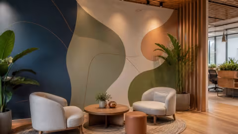 Área de convivência corporativa com mural de formas orgânicas.